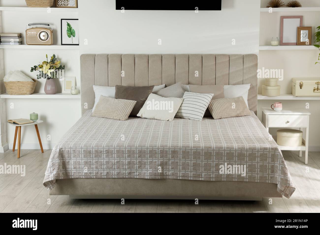 Stilvolle Schlafzimmereinrichtung mit Blumen und dekorativen Elementen auf Regalen Stockfoto