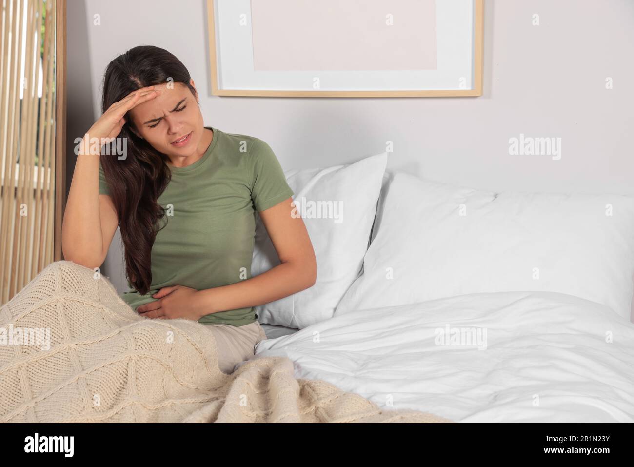 Junge Frau mit Zystitis im Bett zu Hause Stockfoto