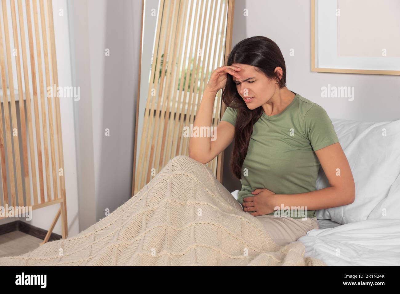 Junge Frau mit Zystitis im Bett zu Hause Stockfoto
