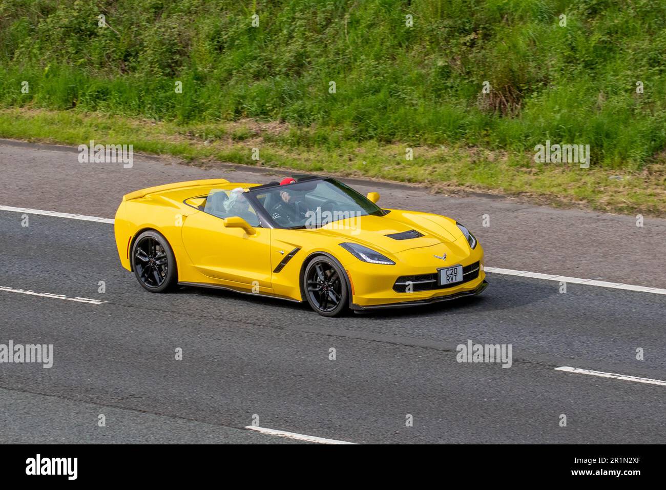 2014 American Chevrolet GMC Corvette, Logo mit gekreuzten Flaggen, Yellow Petrol 6200 ccm, zweitürige, zweisitzige Luxussportwagen; Fahrt auf der Autobahn M61 UK Stockfoto