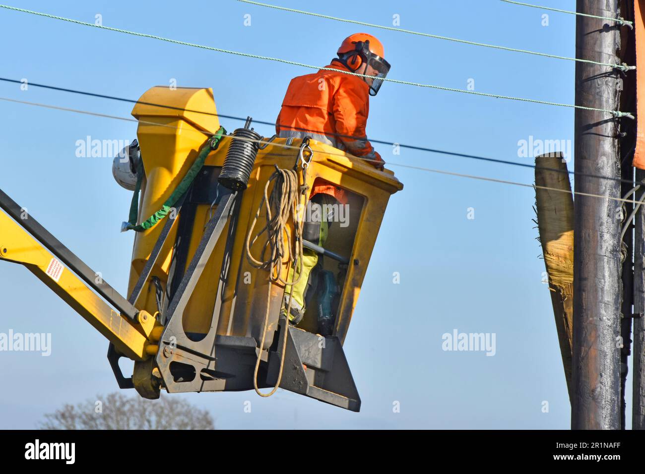 Elektroingenieur an seinem Arbeitsplatz in einem Hebebühne für den Kirschpflücker, der alle Masten und Überlandkabel in der Wohnstraße England UK ersetzt Stockfoto