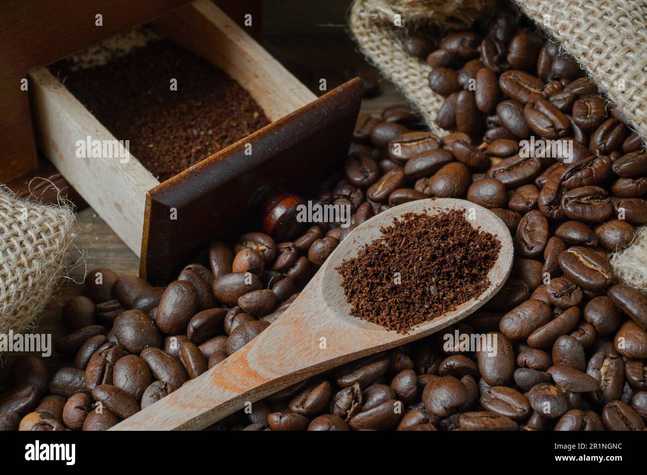 Gemahlener Kaffee auf einem Löffel und geröstete Kaffeebohnen in einem Sack. Stockfoto