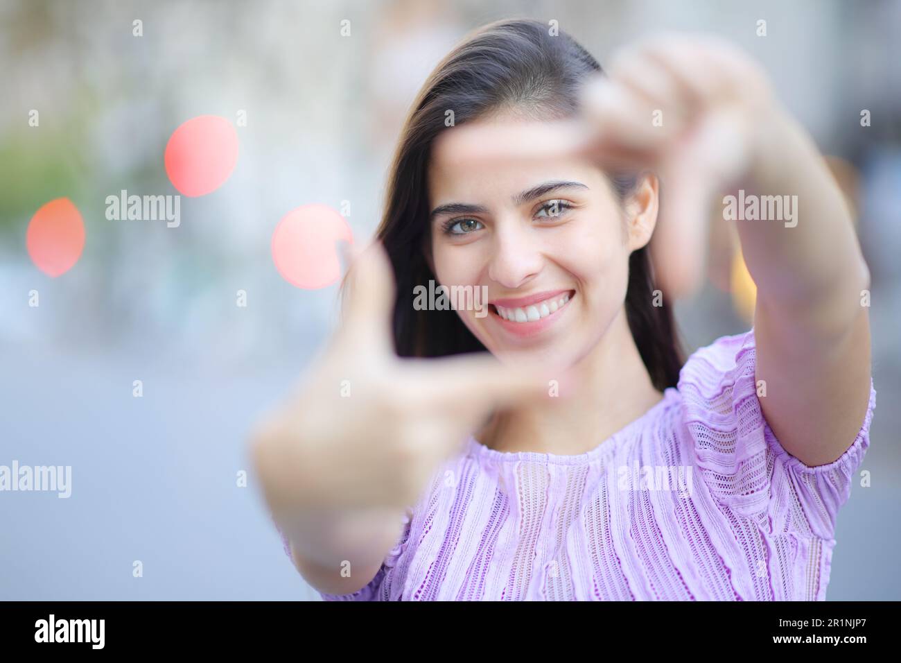 Vorderansicht Porträt einer glücklichen Frau, die mit Händen umrahmt und dich auf der Straße ansieht Stockfoto