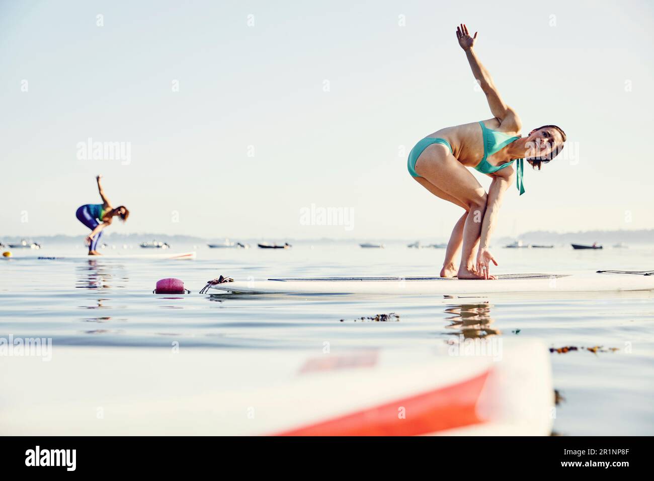 Zwei junge Frauen, die Yoga auf SUP-Brettern machen Stockfoto