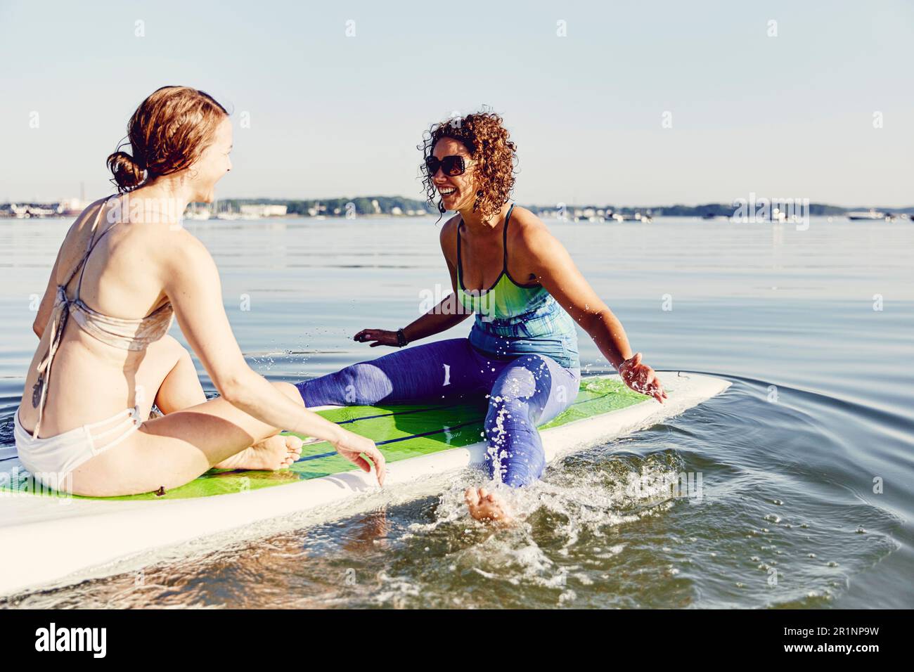Zwei junge Frauen, die Spaß auf einem Stehpaddelbrett haben Stockfoto