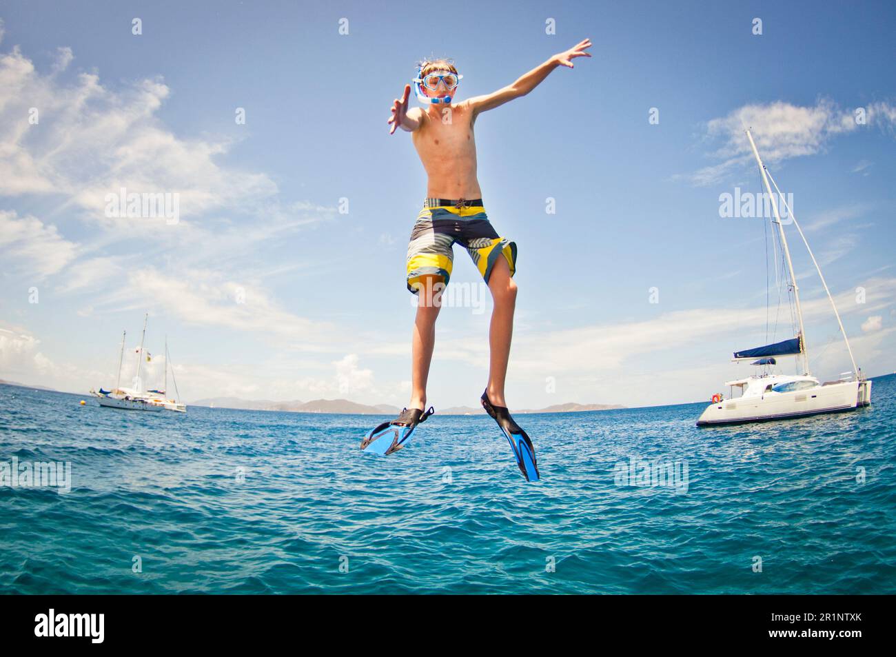 Ein Junge mit Maske und Snokle, der ins Wasser springt. Stockfoto