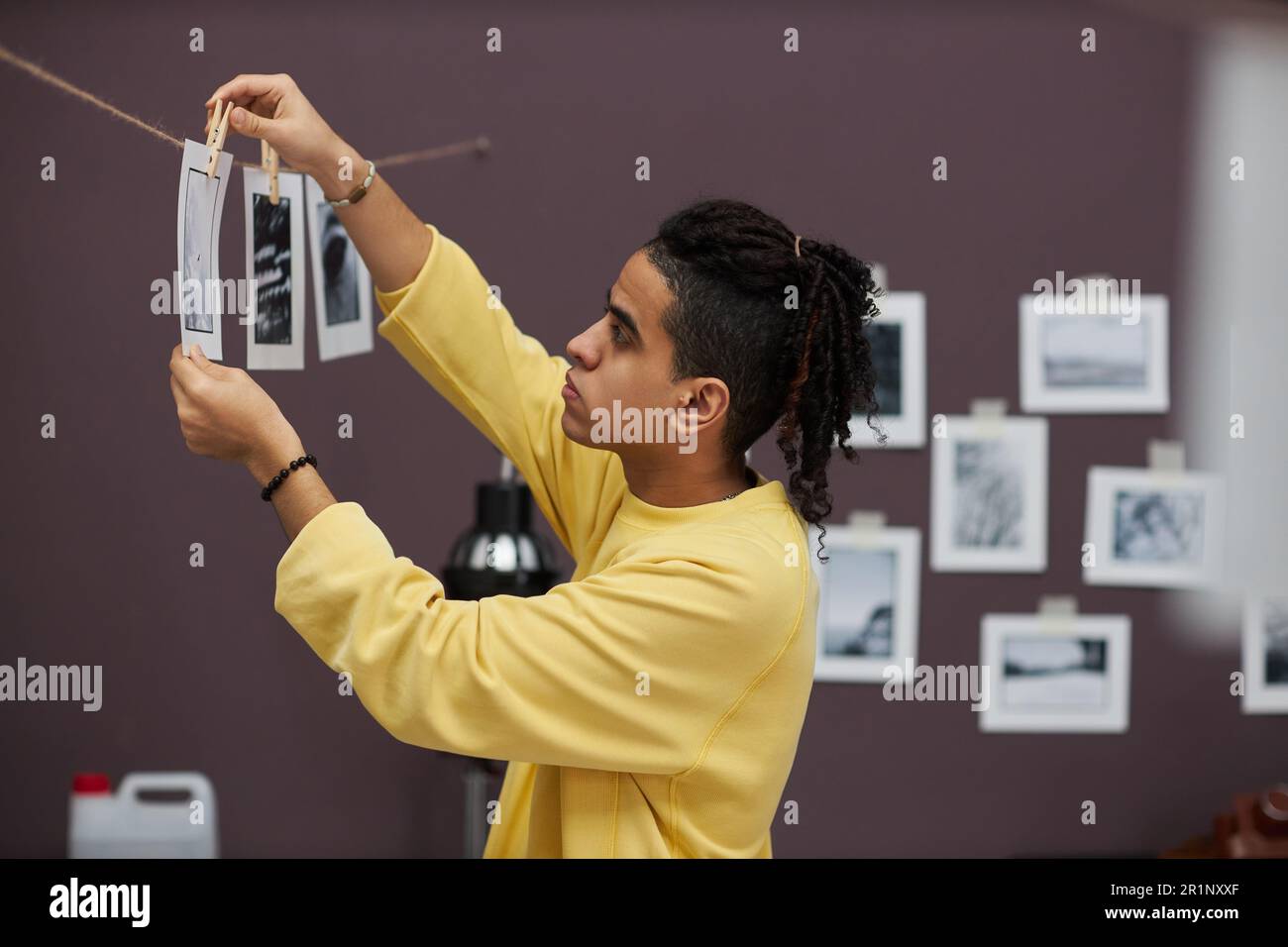 Ein professioneller Fotograf, der Fotos im Fotostudio druckt, hängt fertige Fotos an ein Seil Stockfoto