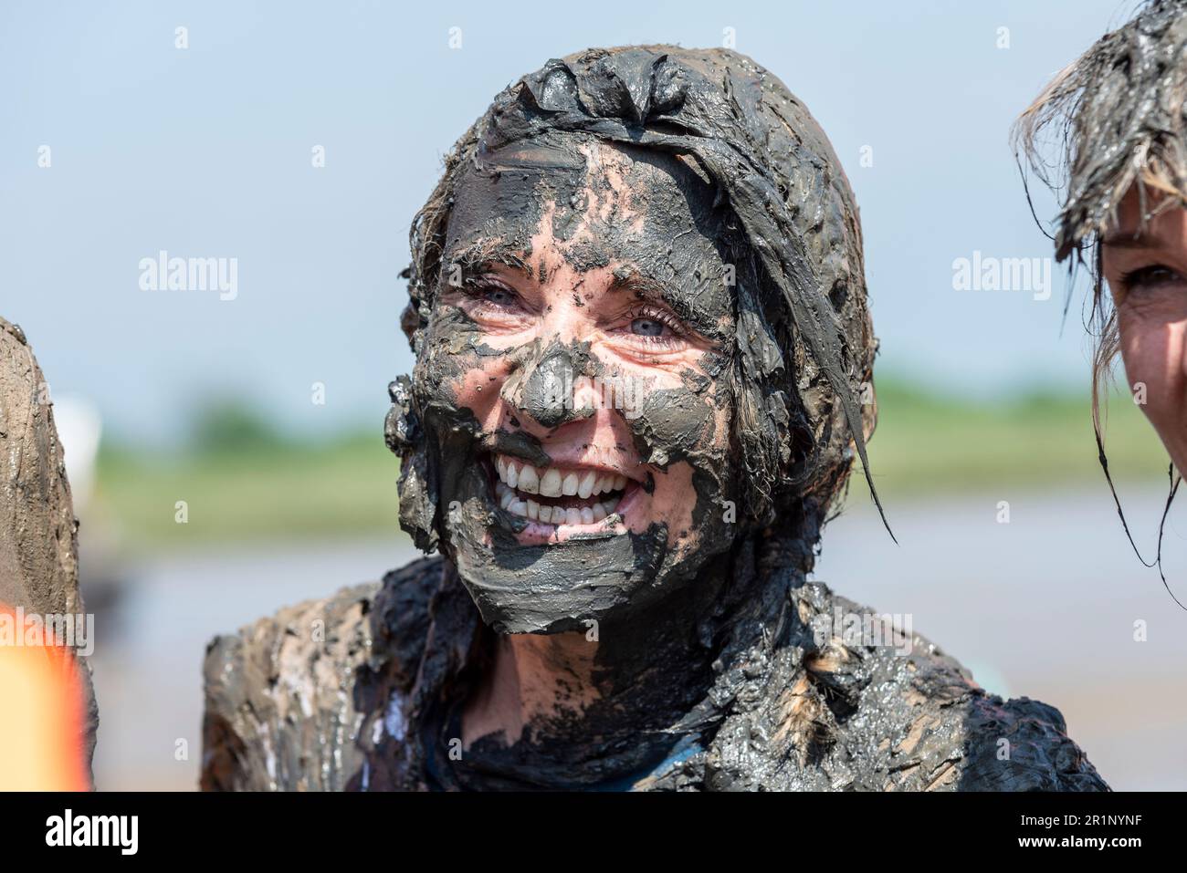 Schlammige Frau nach der Teilnahme am Maldon Mud Race in Maldon, Essex, Großbritannien, im Schlamm des Flusses Blackwater. Traditionelle Wohltätigkeitsveranstaltung Stockfoto