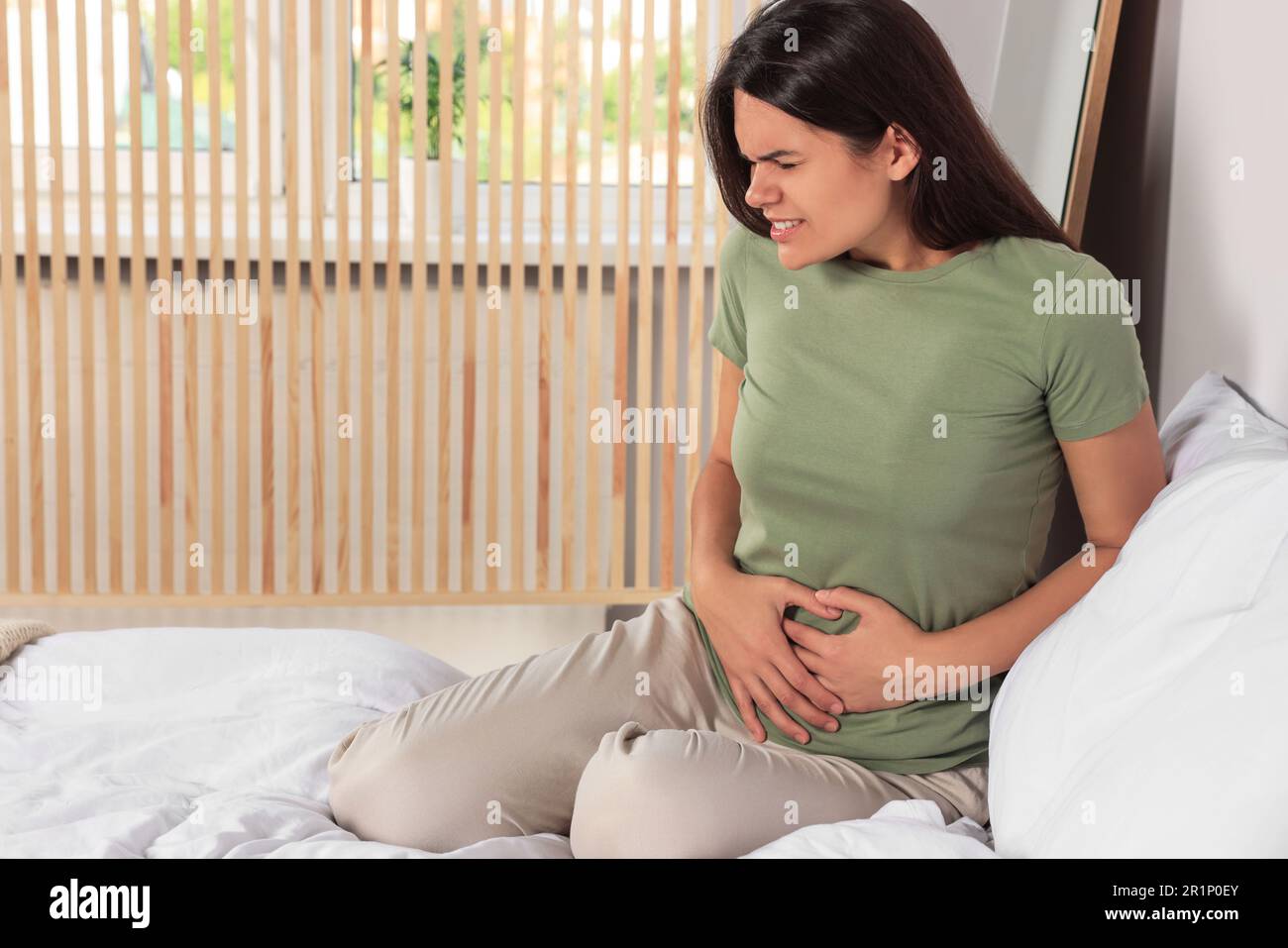 Junge Frau mit Zystitis im Bett zu Hause Stockfoto