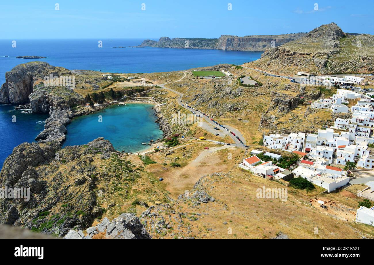 Blick von oben auf die Bucht des Apostels Paul in Lindos auf der Insel Rhodos. Die Straße verläuft neben der Bucht. Die Bucht hat die Form eines Herzens. Stockfoto