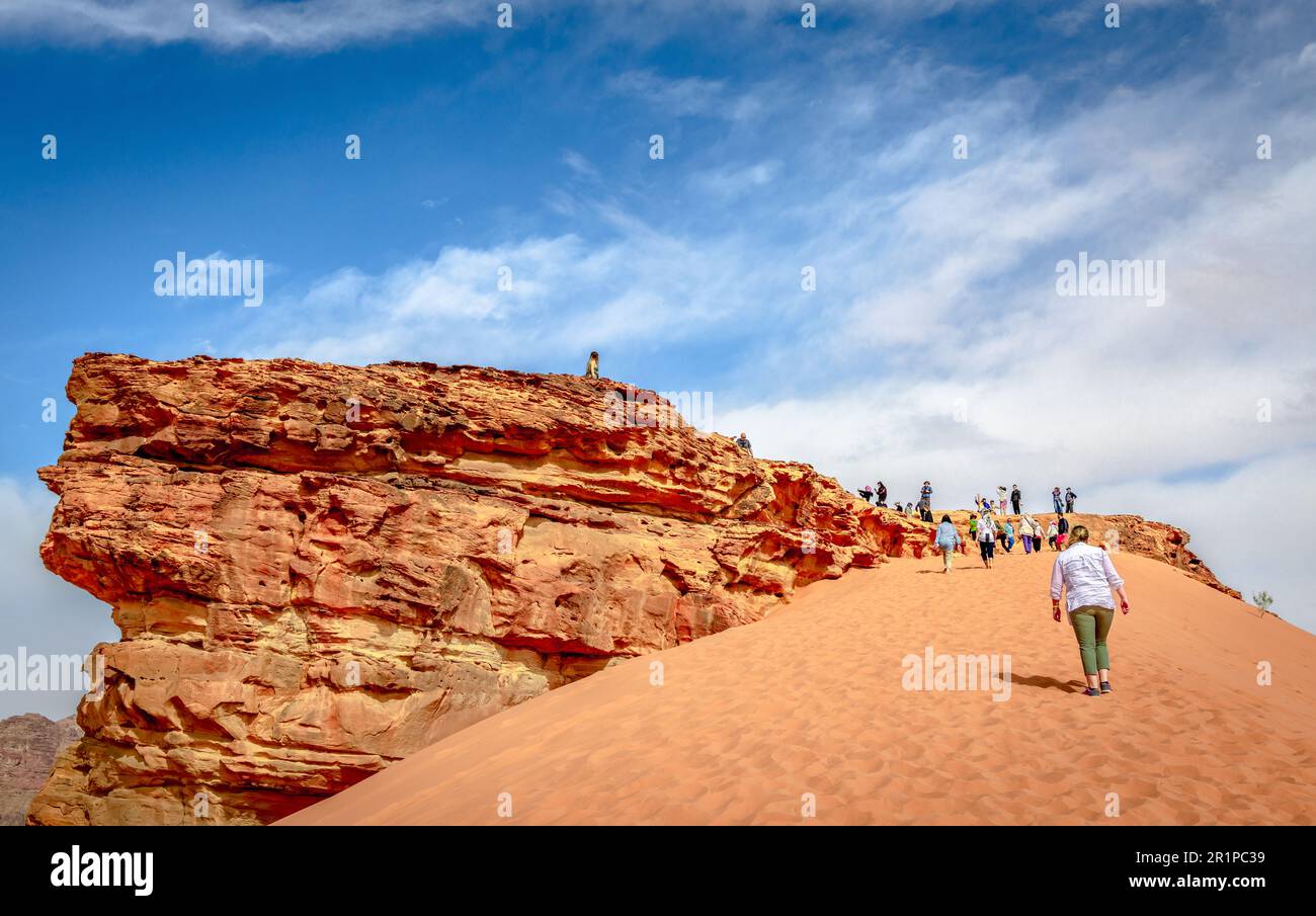 Touristen haben Spaß beim Klettern auf eine Düne in der Wüste von Wadi Rum in Jordanien. Stockfoto