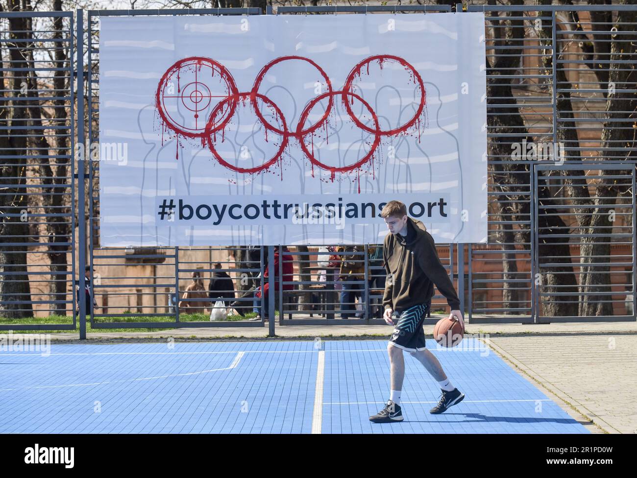 Eine Person spielt Basketball vor dem Hintergrund eines Banners mit der Inschrift #BoycottRussianSport auf einem der Sportplätze in Lemberg. Die Ukraine und viele Länder auf der ganzen Welt fordern, dass russische Athleten wegen des von Russland ausgelösten russisch-ukrainischen Krieges von den Olympischen Spielen und anderen internationalen Wettkämpfen ausgeschlossen werden. Viele ukrainische Athleten, die die Ukraine vor dem russischen Aggressor verteidigten, sind bereits in diesem Krieg gestorben. Zur Unterstützung des Boykotts wurde ein Banner mit der Aufschrift #BoycottRussianSport auf einem der Sportplätze in Lemberg aufgehängt. Stockfoto