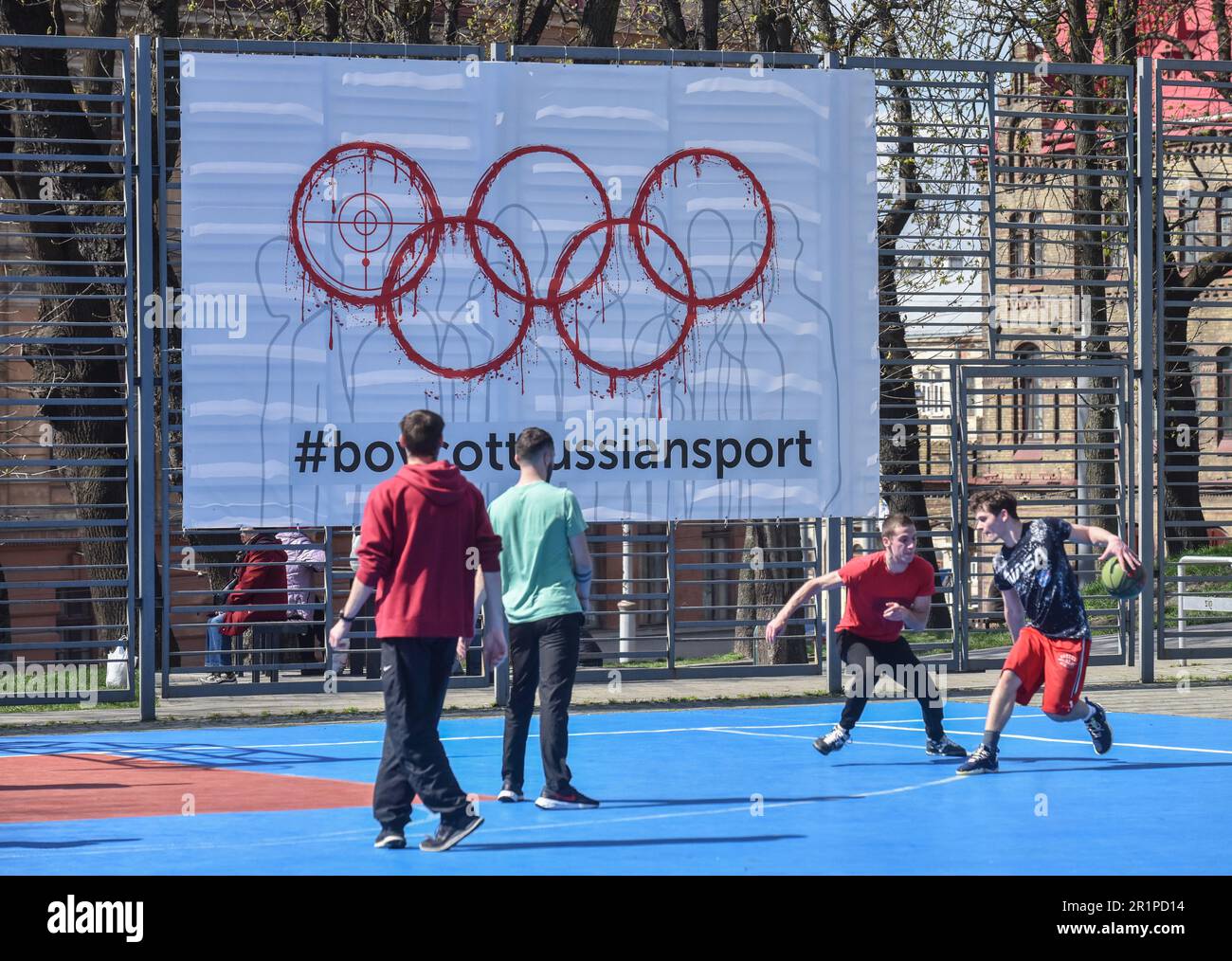 Die Leute spielen Basketball auf dem Hintergrund eines Banners mit der Inschrift #BoycottRussianSport auf einem der Sportplätze in der Lemberg-Ukraine und viele Länder auf der ganzen Welt fordern, dass russische Athleten wegen des von begonnenen russisch-ukrainischen Krieges von den Olympischen Spielen und anderen internationalen Wettkämpfen ausgeschlossen werden Russland. Viele ukrainische Athleten, die die Ukraine vor dem russischen Aggressor verteidigten, sind bereits in diesem Krieg gestorben. Zur Unterstützung des Boykotts wurde ein Banner mit der Aufschrift #BoycottRussianSport auf einem der Sportplätze in Lemberg aufgehängt. Stockfoto