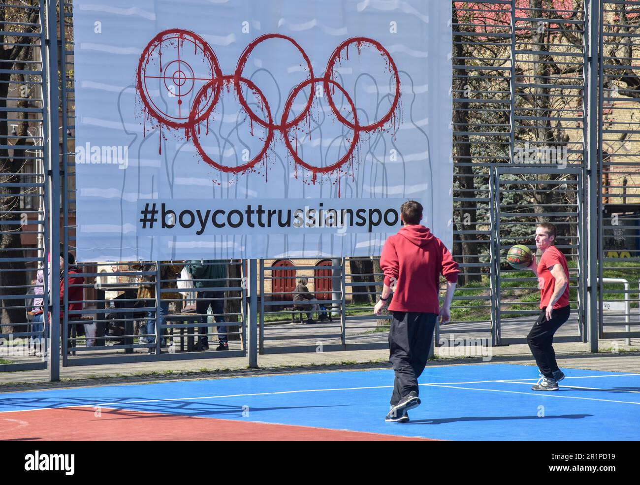 Die Leute spielen Basketball auf einem Banner mit der Inschrift #BoycottRussianSport auf einem der Sportplätze in Lemberg. Die Ukraine und viele Länder auf der ganzen Welt fordern, dass russische Athleten wegen des von Russland ausgelösten russisch-ukrainischen Krieges von den Olympischen Spielen und anderen internationalen Wettkämpfen ausgeschlossen werden. Viele ukrainische Athleten, die die Ukraine vor dem russischen Aggressor verteidigten, sind bereits in diesem Krieg gestorben. Zur Unterstützung des Boykotts wurde ein Banner mit der Aufschrift #BoycottRussianSport auf einem der Sportplätze in Lemberg aufgehängt. Stockfoto