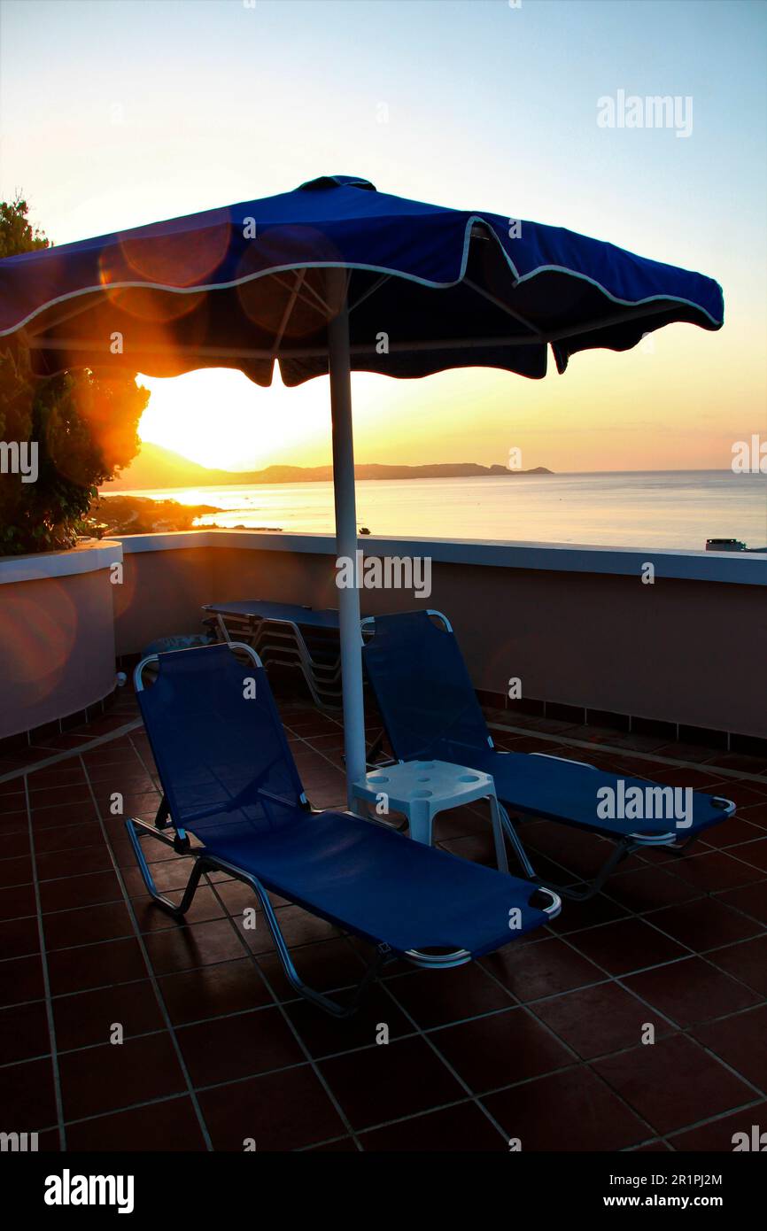 Blick auf den Sonnenaufgang, im Vordergrund 2 Sonnenliegen und einen Sonnenschirm, Wand, Strand, Küste, Meer, Kiotari, Rhodos, Griechenland Stockfoto