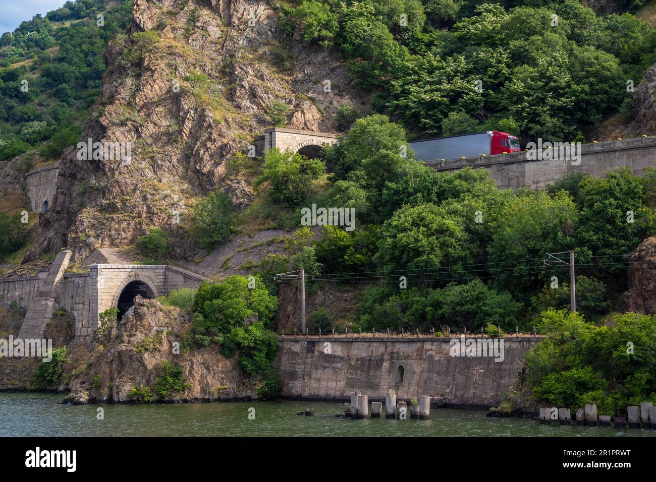 Entlang der Eisernen Tor-Schlucht an der Donau in Rumänien führen Schienen- und Straßenverbindungen. Tunnel und Routen schneiden durch die Felsen an den Klippen. Stockfoto