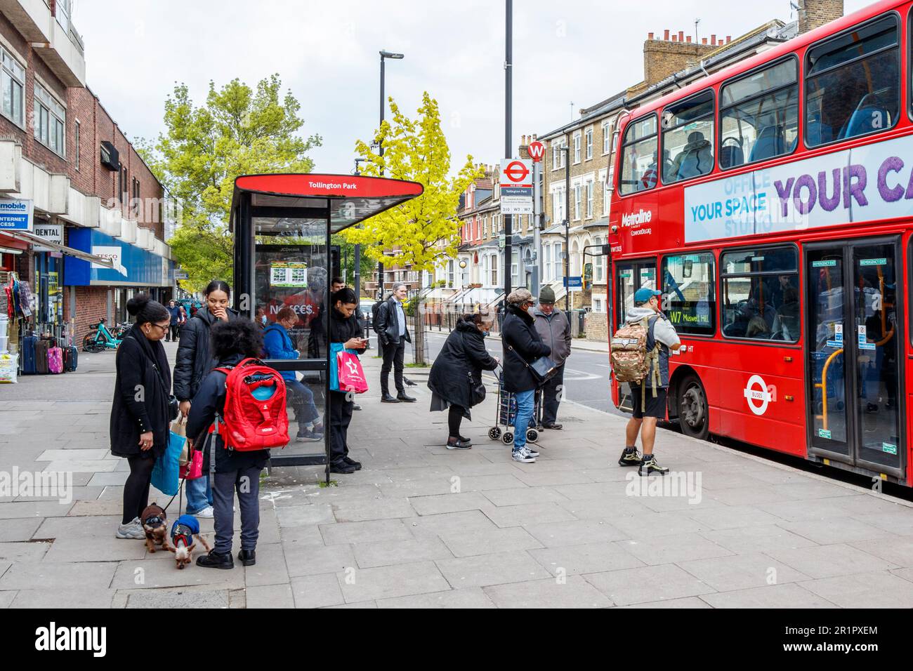 Leute, die an einer Bushaltestelle auf der Stroud Green Road, North London, Großbritannien, in einen Bus einsteigen wollen Stockfoto