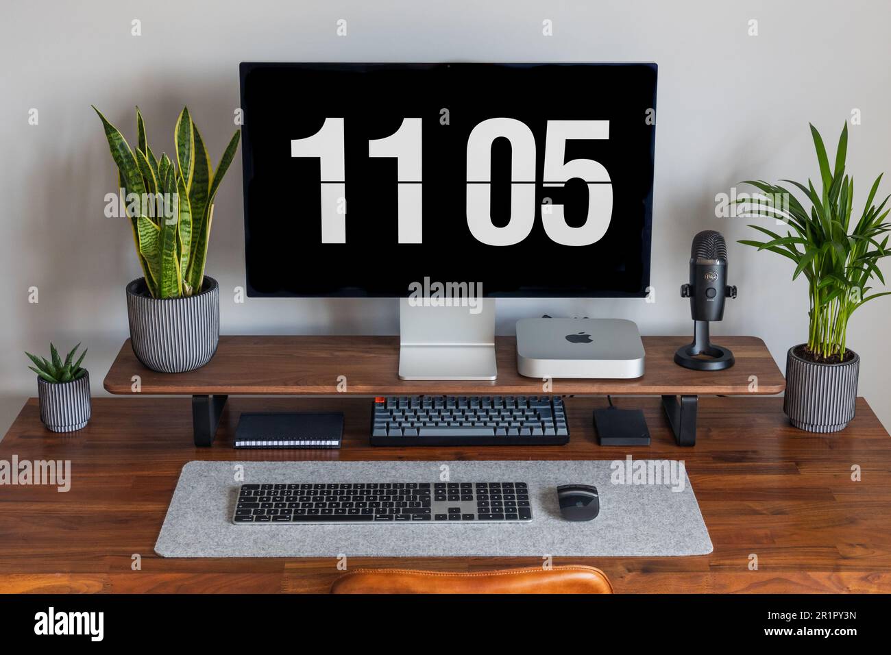 LONDON – 15. MAI 2023: Minimaler Schreibtischeinsatz in einem modernen Heimbüro mit Pflanzen, Walnussholz, Apple Mac Mini-Computer mit Logo Stockfoto