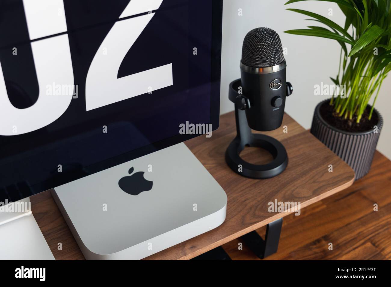 LONDON – 15. MAI 2023: Minimaler Schreibtischeinsatz in einem modernen Heimbüro mit Pflanzen, Walnussholz, Apple Mac Mini-Computer mit Logo Stockfoto