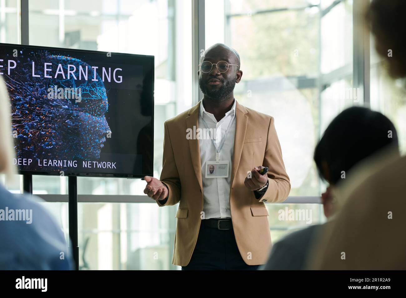 Junger schwarzer Mann in formeller Kleidung steht an interaktivem Brett, während er dem Publikum während der Konferenz die Punkte seiner Präsentation erläutert Stockfoto