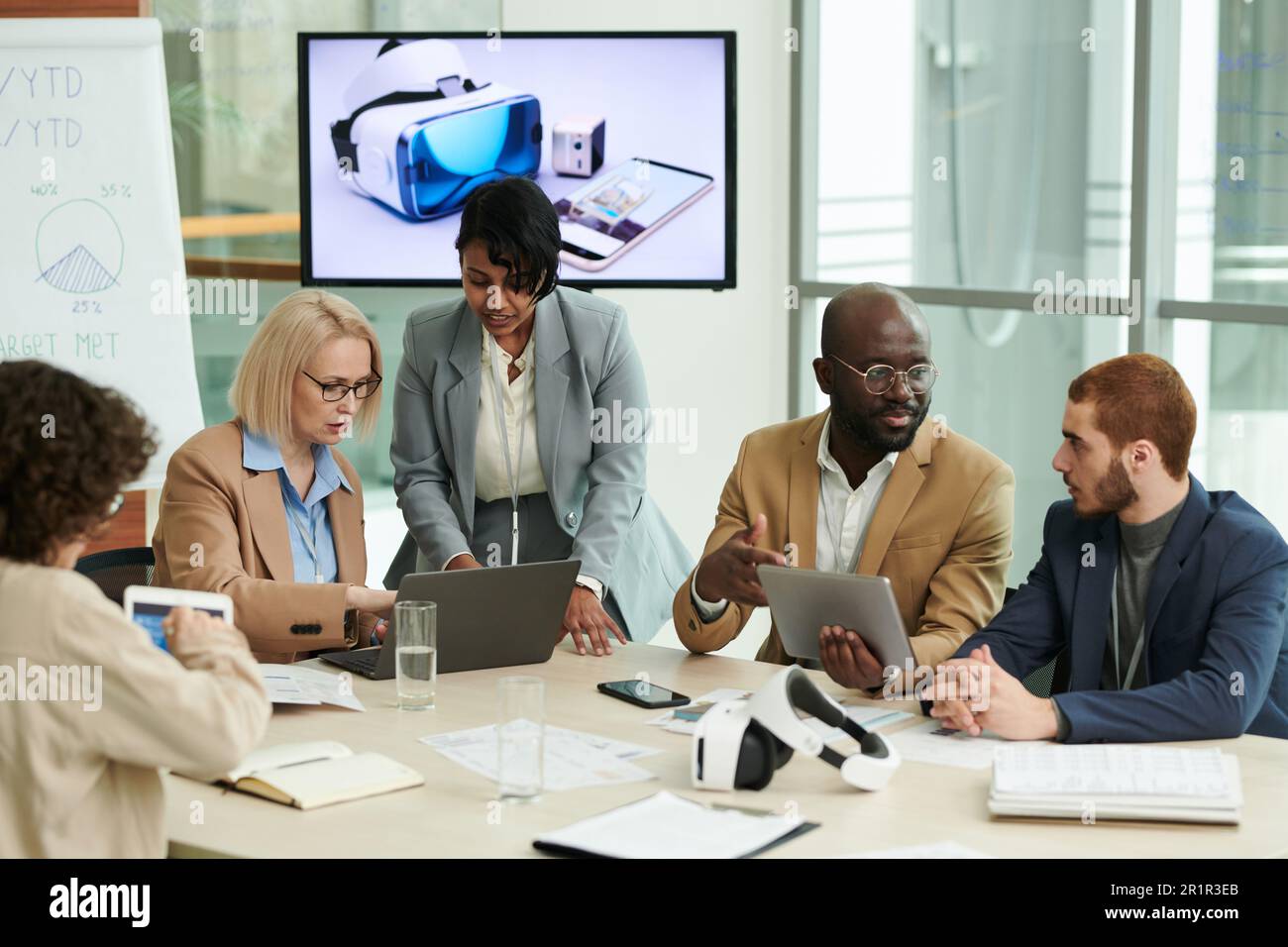 Gruppe interkultureller Mitarbeiter mit mobilen Geräten, die Arbeitspunkte bei Meetings besprechen oder Präsentationen für Konferenzen vorbereiten Stockfoto