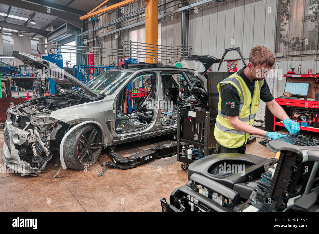 Sie auseinandernehmen. Ein Techniker, der Teile für das Recycling von Fahrzeugen bei einem modernen Demontageunternehmen entfernt. Charles Trent Ltd, Poole, Dorset, Vereinigtes Königreich Stockfoto