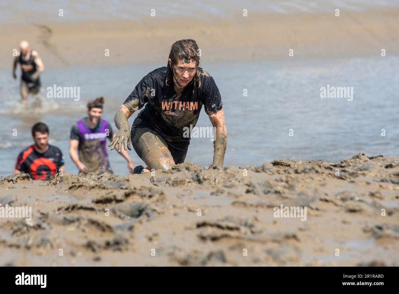 Vicki Riley, Gewinnerin kurz vor dem Ende des Maldon Mud Race in Maldon, Essex, Großbritannien, im Schlamm des Flusses Blackwater. Traditionelle Wohltätigkeitsveranstaltung Stockfoto