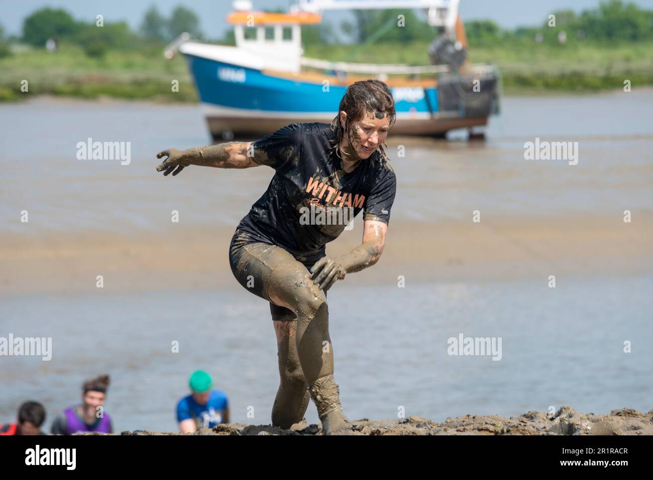 Vicki Riley, Gewinnerin kurz vor dem Ende des Maldon Mud Race in Maldon, Essex, Großbritannien, im Schlamm des Flusses Blackwater. Traditionelle Wohltätigkeitsveranstaltung Stockfoto