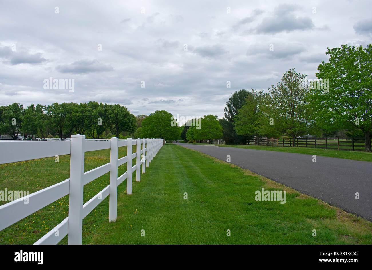 Leere Straße in Colts Neck, New Jersey, USA, an einem düsteren Frühlingstag mit bedrohlichen Wolken -02 Stockfoto