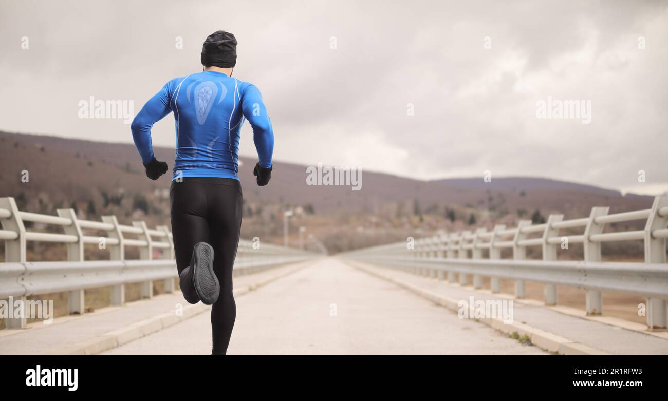 Heckaufnahme eines Mannes in Sportkleidung, der auf einer Brücke läuft Stockfoto