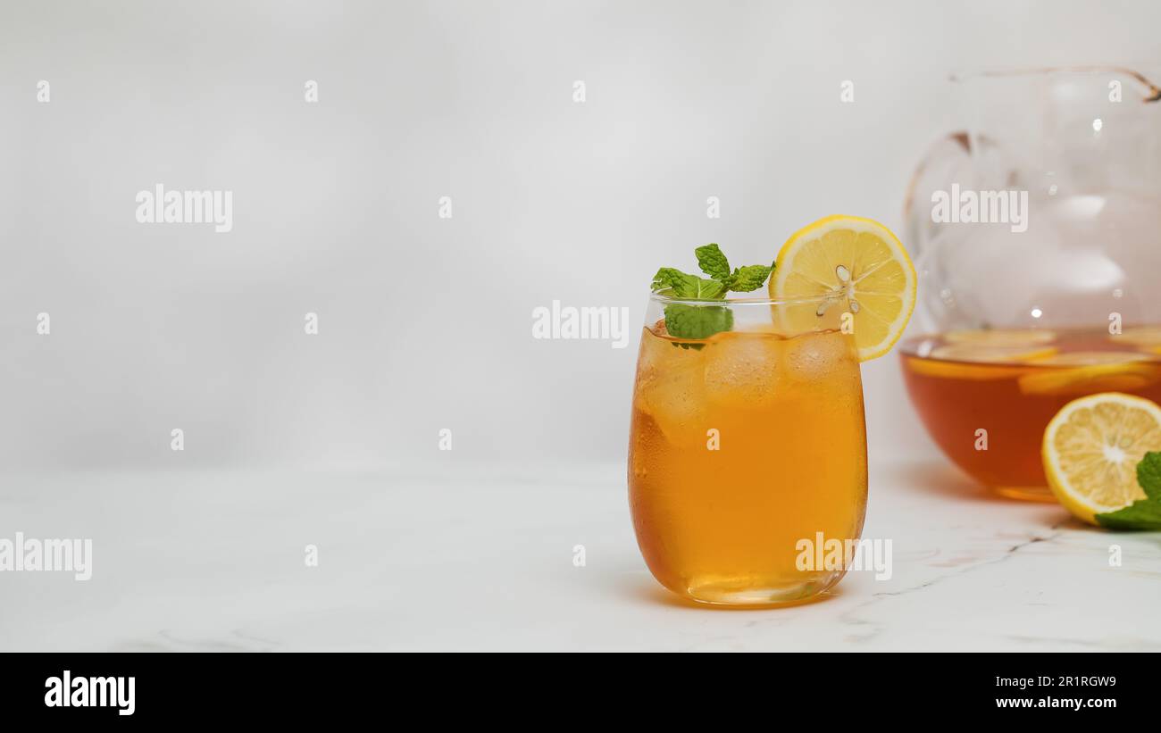 Ein Glas kalten Tee, Eiswürfel, Zitronenscheiben und einen Pfefferminzzweig. Kühle Sommergetränke. Stockfoto
