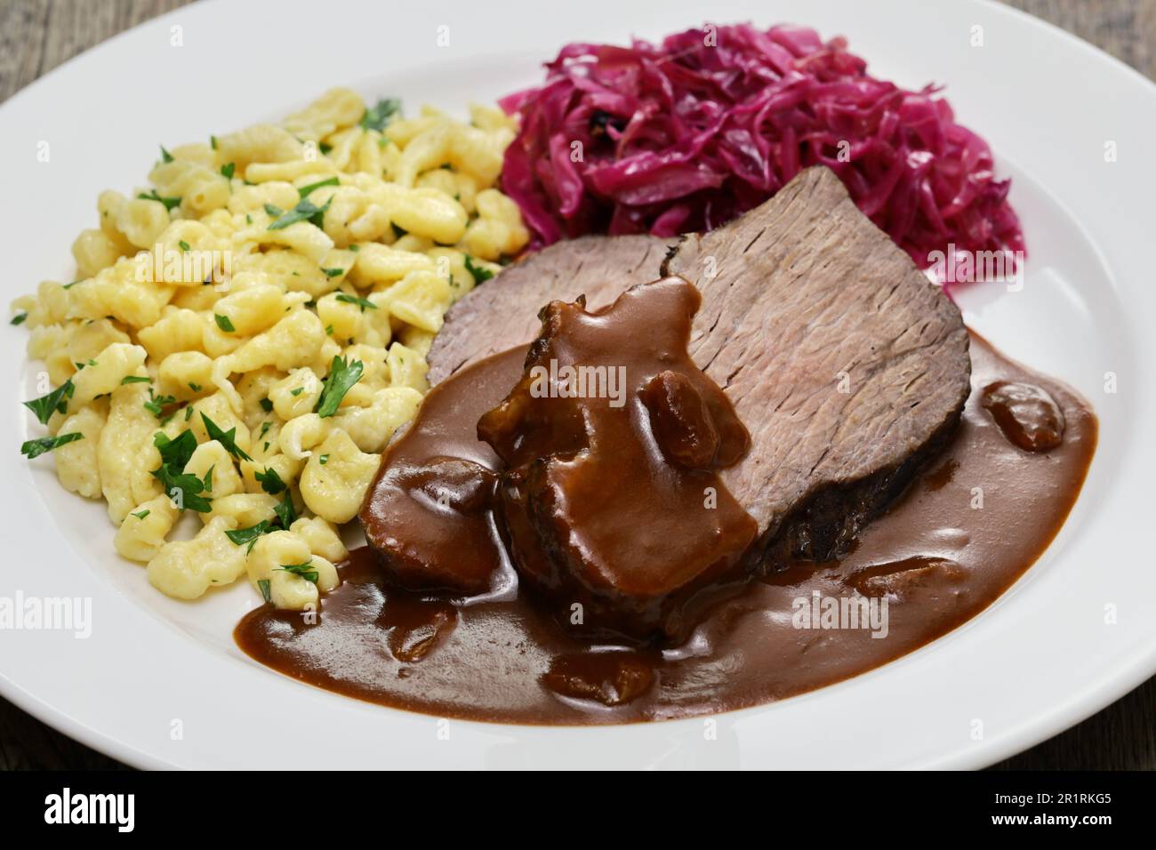 Sauerbraten (zartiertes Rindfleisch, das mehrere Tage in Essig und Gemüse mariniert und dann geschmort wurde), Rotkohl (geschmorter Rotkohl), Spaetzle (kleine Vergangenheit Stockfoto