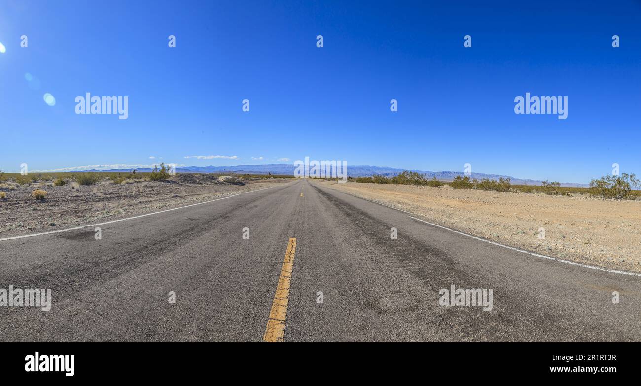 Panoramablick auf eine Straße durch die Wüste aus der Perspektive des Bodens Stockfoto