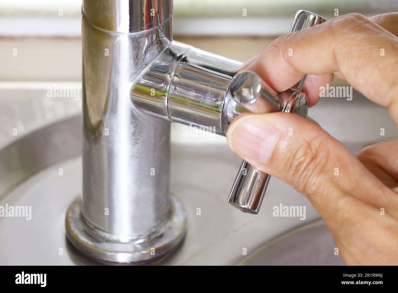 Person, die einen Wasserhahn zum Händewaschen aufdreht Stockfoto