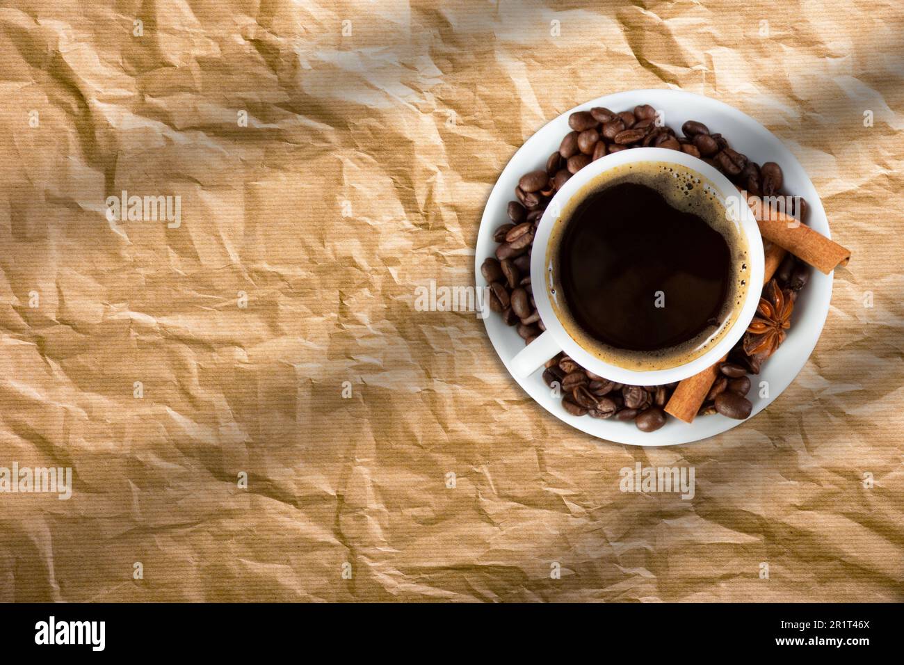 Draufsicht einer Tasse Kaffee mit Kaffeebohnen und Zimtstangen auf Brotpapier isoliert. Stockfoto