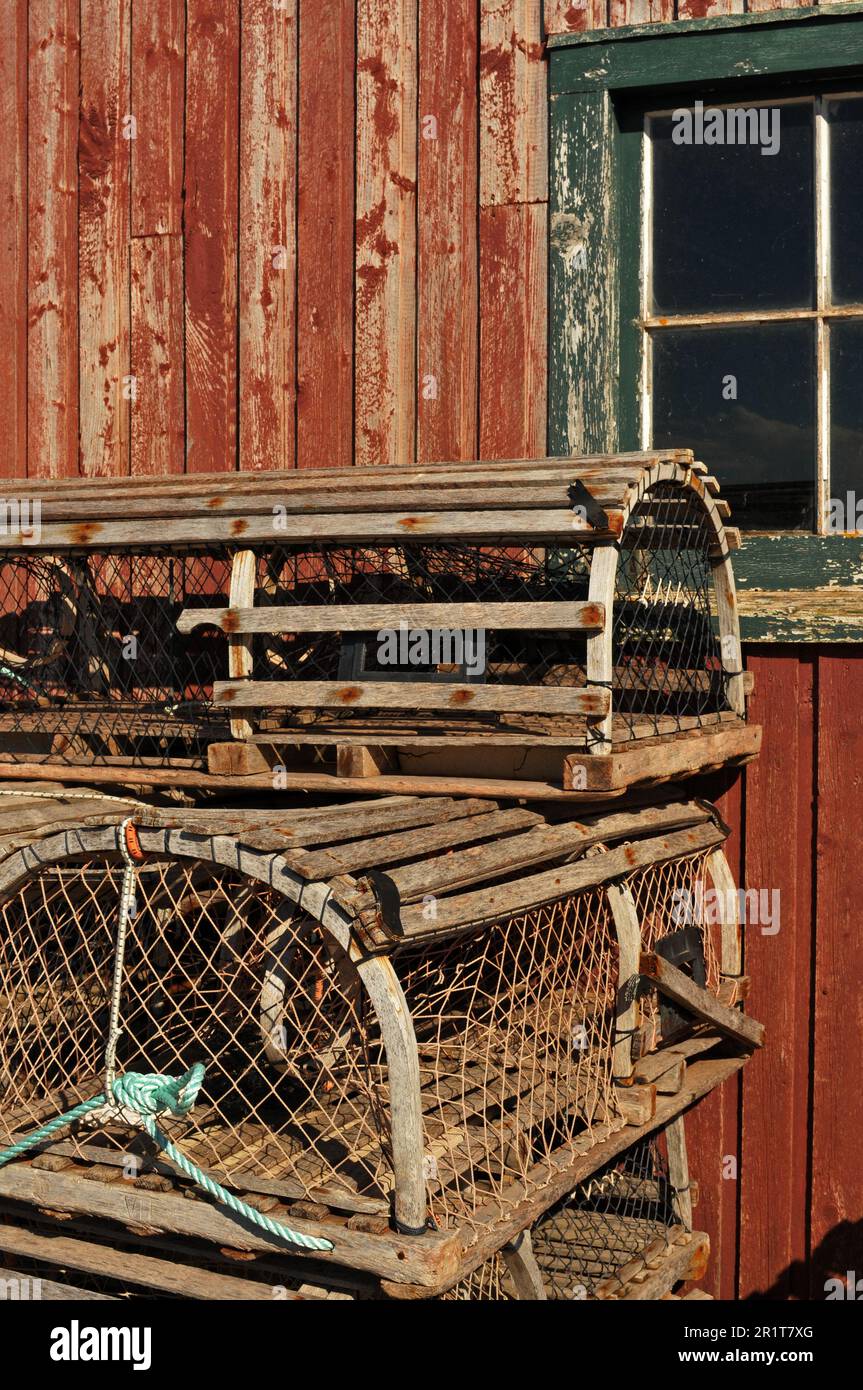 Traditionelle Hummerfallen aus Holz werden in einem Fischerdorf in Prince Edward Island, Kanada, vor einem Schuppenfenster gestapelt. Stockfoto
