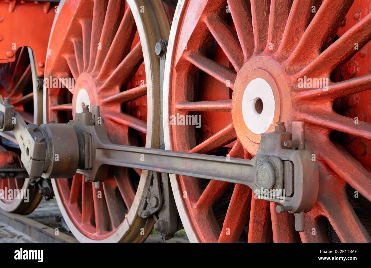 Große rote Räder, Schwungräder, Pleuelstangen und andere Maschinen einer alten Dampflokomotive. Stockfoto