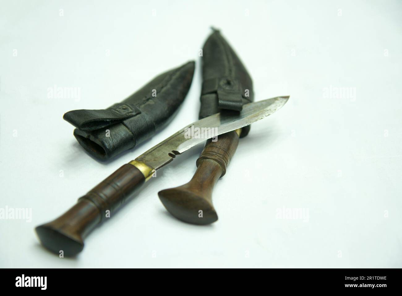Ein Messer und eine Messerabdeckung liegen auf einer weißen Oberfläche. Nepali-Khukuri-Messer Stockfoto