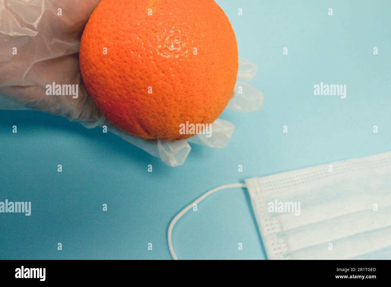 Ein Arzt in Einweg-Schutzhandschuhen hält eine Orange in der Hand für den Patienten. Vitamin C zur Bekämpfung von Virusinfektionen und Temperatur zur Erhöhung der imm Stockfoto