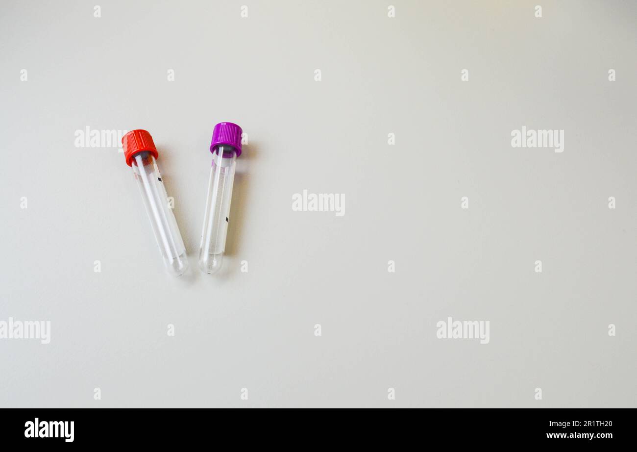 Zwei Reagenzgläser mit einem roten und violetten Verschluss auf weißem Hintergrund. Sterile Einwegröhrchen für die Entnahme von venösem Blut. Labordiagnostik, Blut Stockfoto
