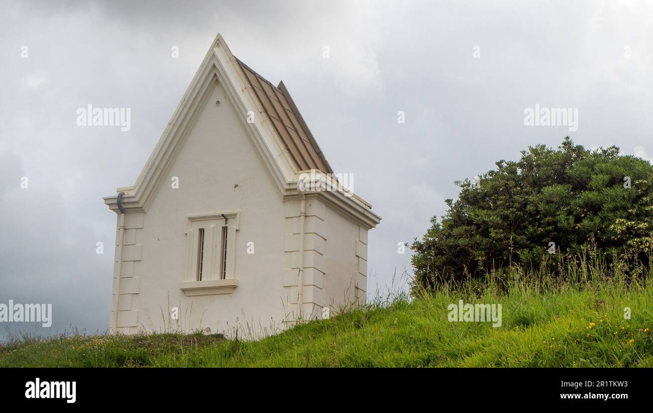 Ein kleines weißes Haus auf einem grünen Hügel Stockfoto