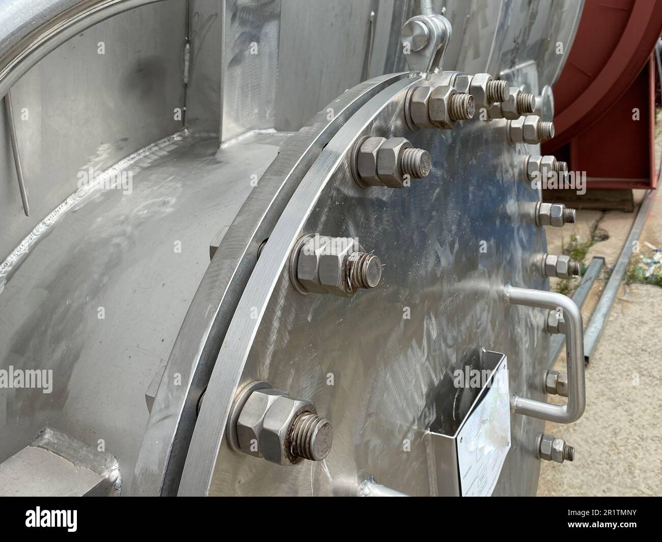 Großer runder Mannlochdeckel aus glänzendem Eisen mit Schrauben und Muttern für den Wärmetauscher von Muscheln und Rohren oder industrielle Edelstahlsäule für Raffineriehunde Stockfoto