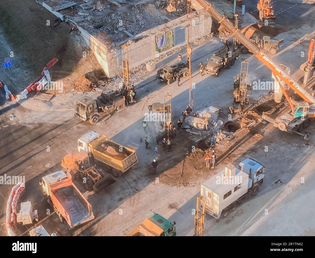 Bau einer neuen Überführung im Stadtzentrum auf einer verschneiten Straße. Straßenreparaturen, gelbe Kipplaster transportieren Asphalt, Sand für die Straßenbefestigung. Stockfoto