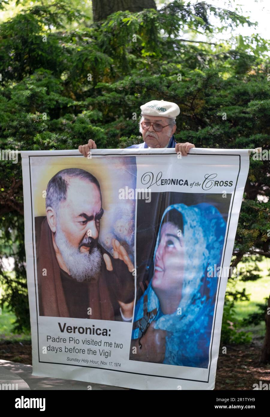 Bei einer Krönungszeremonie im Mai hält ein frommer römisch-katholischer Katholik ein Banner mit Fotos von Veronica Lueken und Padre Pio. In Flushing Meadows Corona Park in NYC. Stockfoto