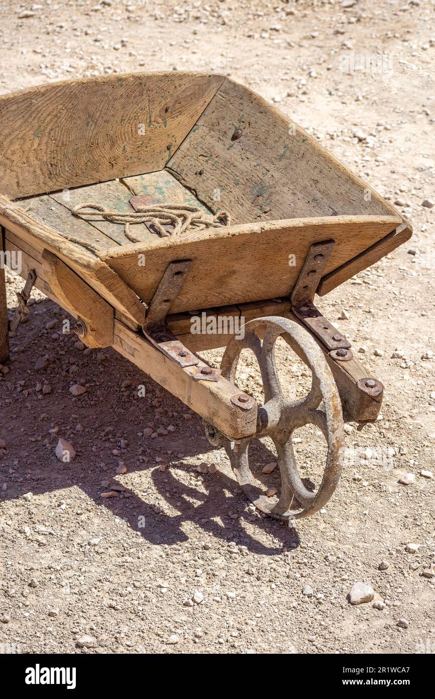 Vertikalansicht einer alten Holzkarre mit verschlissenem Eisenrad im Laufe der Zeit Stockfoto