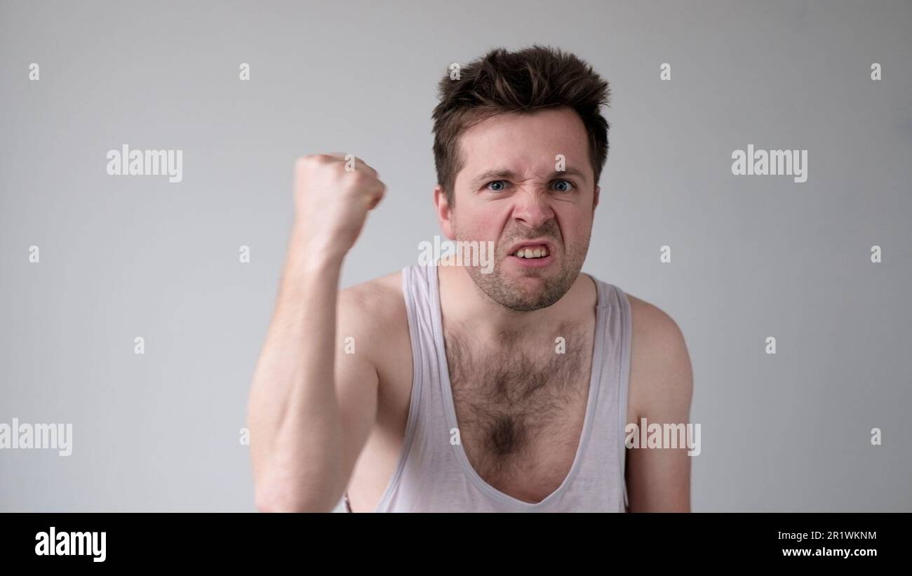Der junge europäische Mann verhält sich aggressiv, schikaniert ein wütendes Gesicht und bedroht jemanden Stockfoto