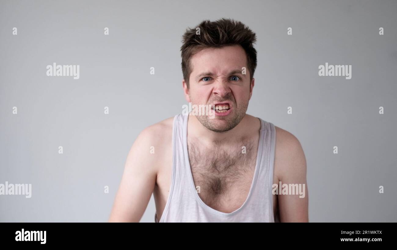 Der junge europäische Mann verhält sich aggressiv, schikaniert ein wütendes Gesicht und bedroht jemanden Stockfoto