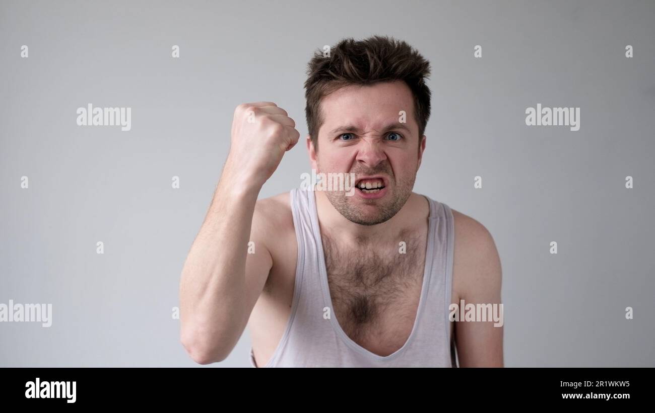 Der junge europäische Mann verhält sich aggressiv, schikaniert ein wütendes Gesicht und bedroht jemanden Stockfoto