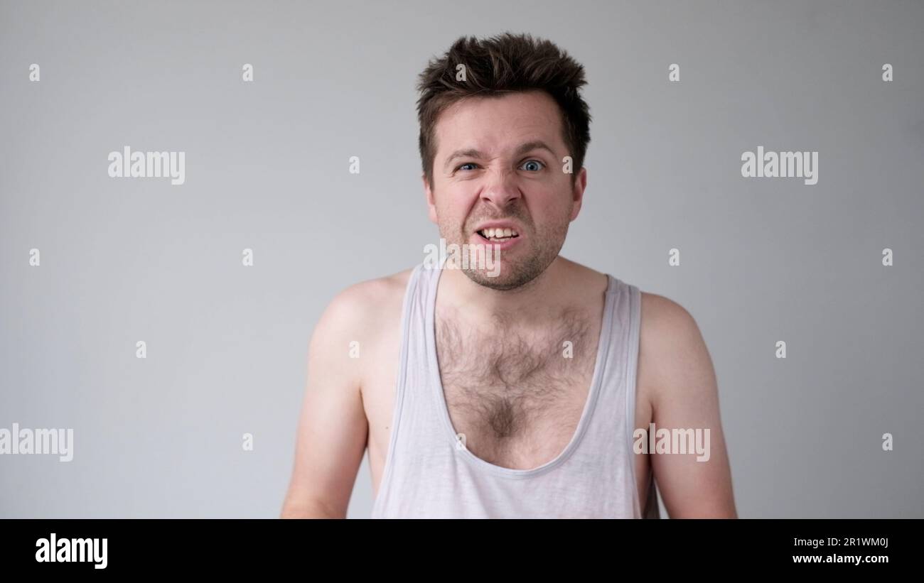 Der junge europäische Mann verhält sich aggressiv, schikaniert ein wütendes Gesicht und bedroht jemanden. Studioaufnahme Stockfoto