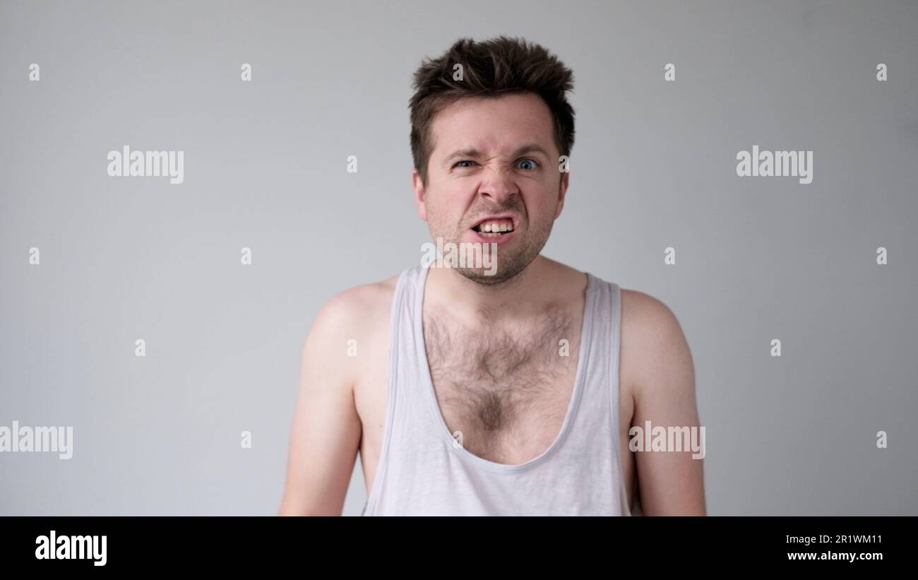 Der junge europäische Mann verhält sich aggressiv, schikaniert ein wütendes Gesicht und bedroht jemanden Stockfoto